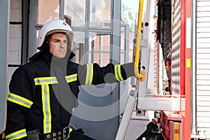 Firefighter in uniform and helmet near fire truck