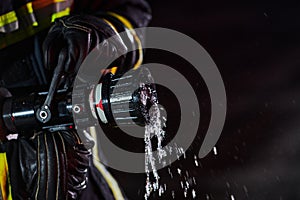 Firefighter using a water hose to eliminate a fire hazard. Team of firemen in the dangerous rescue mission.