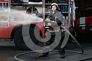 Firefighter with water hose near truck