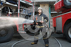 Firefighter with water hose near truck