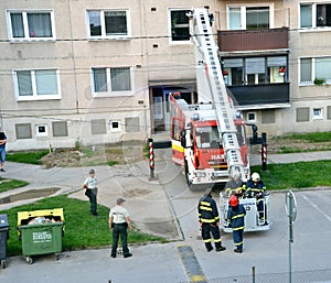 Firefighters in action, two of them get aboard into telescopic boom basket. Two police officers stand next to the fire truck