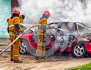 Firefighters extinguish a burning car, fire and car