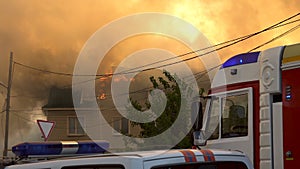 Firefighters extinguish a three-story house. Fire engines on a background of a burning building