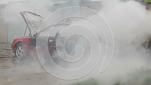 Firefighters or firemen with hose extinguish a burning car after autoignition