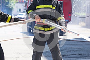 Firefighters holding firehose to extinguish fire photo