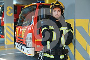 Firefighters man in a protective suit near fire truck. Protection, rescue from danger. Fire station