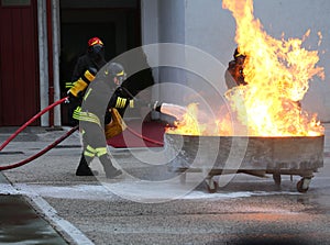 Firefighters with oxygen tank extinguishing a fire with foam
