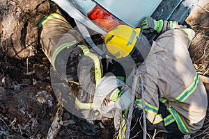 Firefighters rescuing fallen car in ditch