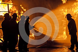 Firefighters spraying burning structure with water