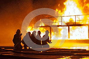 Firefighters spraying down burning structure during firefighting exercise