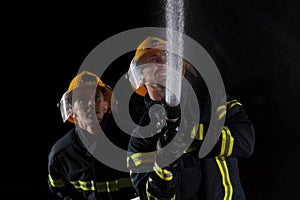 Firefighters use a water hose to eliminate a fire hazard. Team of firemen in the dangerous rescue mission.