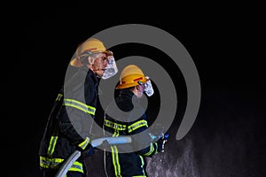 Firefighters using a water hose to eliminate a fire hazard. Team of female and male firemen in dangerous rescue mission