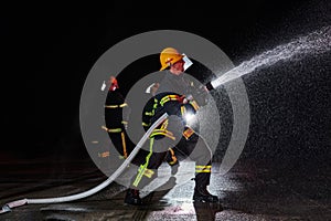 Firefighters using a water hose to eliminate a fire hazard. Team of female and male firemen in dangerous rescue mission