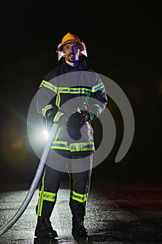 Firefighters using a water hose to eliminate a fire hazard. Team of female and male firemen in dangerous rescue mission