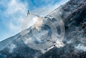 Firefighting Aircraft and Helicopter dropping the water for fighting a fire on mountain