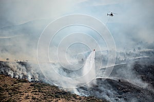 Firefighting helicopter drop water on forest fire