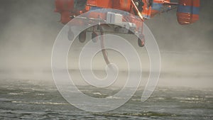 Firefighting helicopter  hovering over the lake to refills water