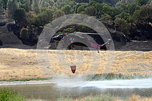 Firefighting helicopter refills water bucket