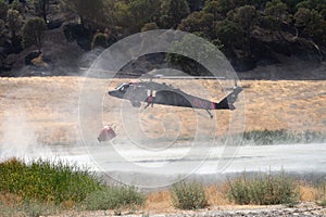 Firefighting helicopter refills water bucket