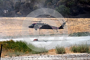 Firefighting helicopter refills water bucket