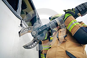 Fireman cuts the sheet metal with pliers, at car accident scene