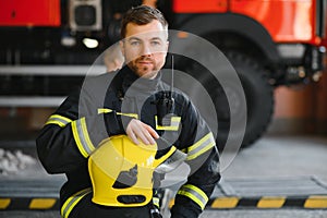 Fireman & x28;firefighter& x29; in action standing near a firetruck. Emergency safety. Protection, rescue from danger.