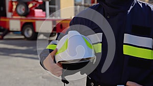 Fireman with helmet near fire engine. Concept of saving lives, heroic profession, fire safety