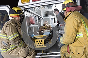 Fireman Looking At Patient And EMT Doctor photo