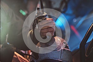 Fireman in a protective uniform sitting in the fire truck and holding walkie-talkie. Hand close up.