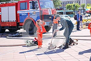 A fireman`s man is teaching a little girl in an ornery fireproof suit to run around with Belarus, Minsk, 08.08.2018