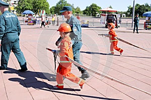 A fireman`s man is teaching a little girl in an ornery fireproof suit to run around with Belarus, Minsk, 08.08.2018