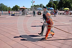 A fireman`s man is teaching a little girl in an ornery fireproof suit to run around with Belarus, Minsk, 08.08.2018