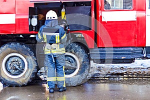 A fireman standing near a red fire engine and holding an oxygen