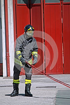Fireman while unrolls a fire hose to extinguish the flames