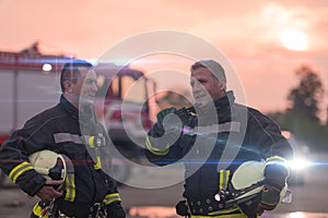 Fireman using walkie talkie at car traffic rescue action fire truck and fireman's team in background.