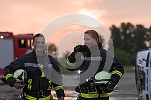 fireman using walkie talkie at rescue action fire truck and fireman& x27;s team in background.