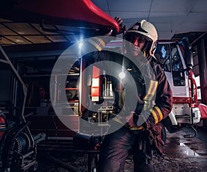 A fireman wearing a protective uniform with flashlight included working in a fire station garage