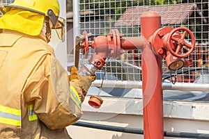 Fireman in yellow fire fighter uniform during connect firehose tube in to fire hydrant