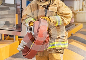 Fireman in yellow fire fighter uniform with rolled fire hose during prepare connect firehose tube in to fire hydrant