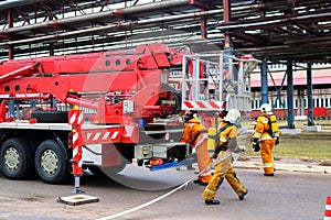 Firemen rescue workers in fireproof suits came to extinguish a fire in a fire truck and stretch the hoses in a large industrial