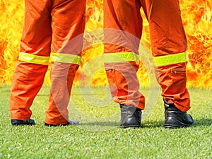 Firemen standing in front of a big flame