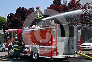 Firemen using water canon on fire truck to put out apartment fire