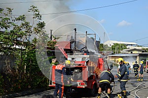 Firemen and volunteers working assembling fire hoses in fire truck in the area of a burning house