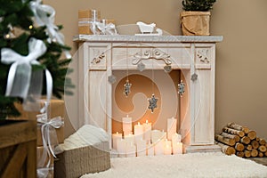 Fireplace with burning candles in room interior. Christmas celebration