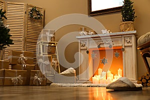 Fireplace with burning candles in room interior. Christmas celebration