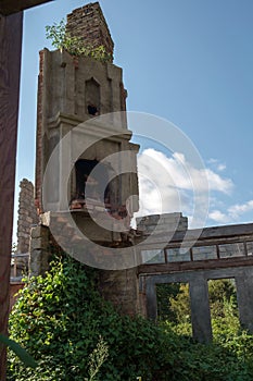 fireplace chimney at the abandoned wrecked house overgrown with green ivy