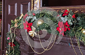 A fireplace is decorated for Christmas with garland, lights and