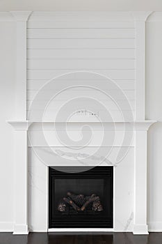 A fireplace detail with decorative trim, marble surround, and shiplap.