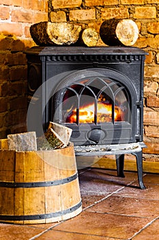 Fireplace with fire flame and firewood in barrel interior. Heating.