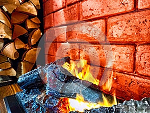 Fireplace. Firebrands, fire and a brick wall on the background. Warm Glow From Firebrands in a Red Brick Fireplace